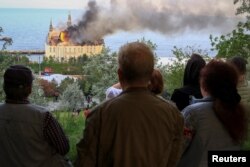 Orang-orang melihat gedung lembaga pendidikan yang terbakar pasca serangan rudal Rusia, di tengah serangan Rusia ke Ukraina, di Odesa, Ukraina, 29 April 2024. (Foto: REUTERS/Sergey Smolentsev)