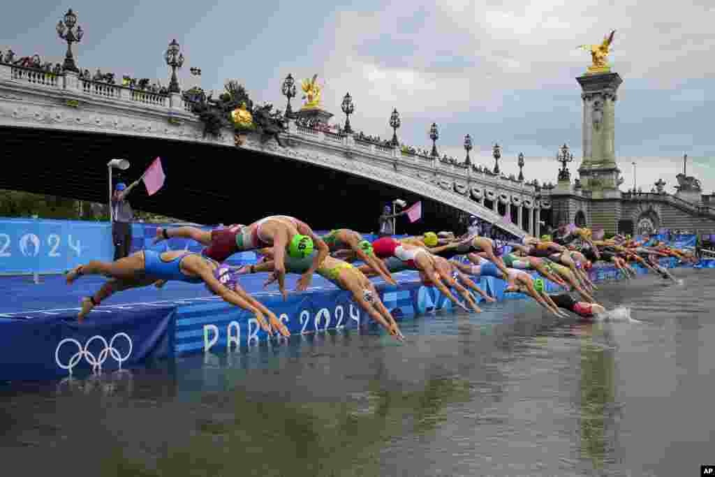 Athletes dive into the water for the start of the women's individual triathlon competition at the 2024 Summer Olympics in Paris, France.