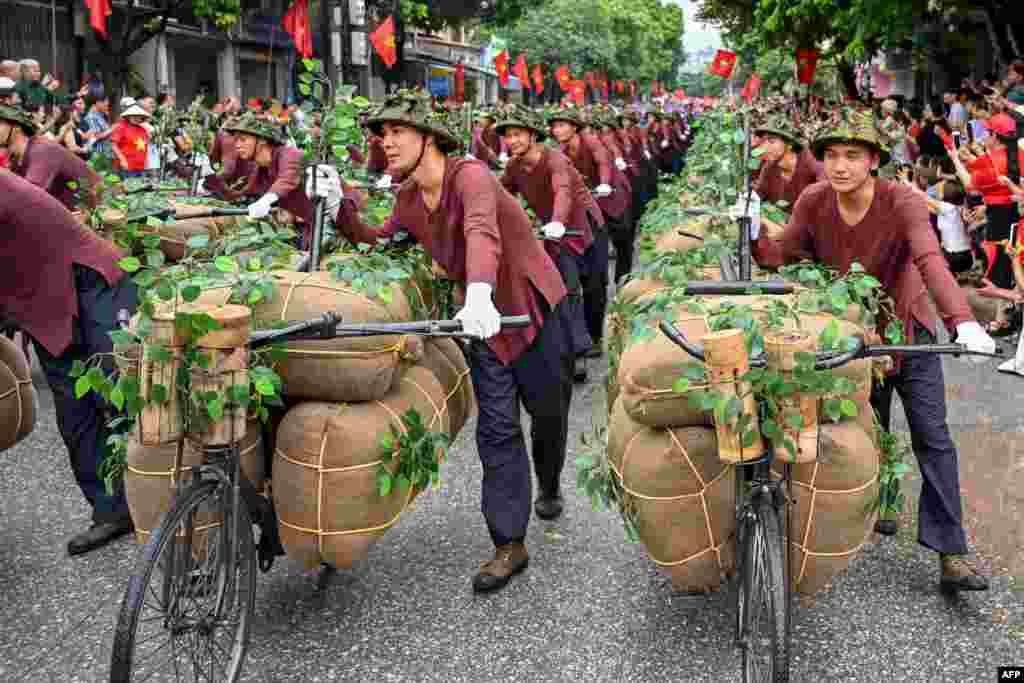 Para pengisi acara berjalan dengan sepeda yang menggambarkan pengangkutan makanan dan kebutuhan ke medan perang pada perayaan resmi peringatan 70 tahun kemenangan Dien Bien Phu tahun 1954 atas pasukan kolonial Prancis di kota Dien Bien Phu, Vietnam.
