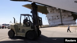Seorang pekerja menurunkan pasokan medis dan barang-barang bantuan dari pesawat kargo dari Uni Emirat Arab untuk bantuan korban banjir di kota Derna dan sekitarnya, di bandara kota Benghazi, Libya15 September 2023. 