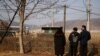 FILE - Seorang pembelot Korea Utara dan anak-anaknya berdiri di depan pagar kawat berduri di dekat zona demiliterisasi yang memisahkan kedua Korea, di Paju, 12 Februari 2021.