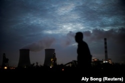 Seorang pria berjalan melewati pembangkit listrik tenaga batu bara di Shanghai, China, 14 Oktober 2021. (Foto: REUTERS/Aly Song)