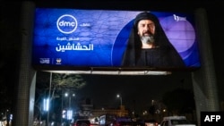 Sejumlah kendaraan bergerak melintasi papan iklan yang menampilkan promo dari serial televisi asal Mesir "al-Hashashin" (Sang Pembunuh) yang terpasang di jalanan Heliopolis di Kairo, Mesir, pada 3 Maret 2024. (Foto AFP/Amir Makar)