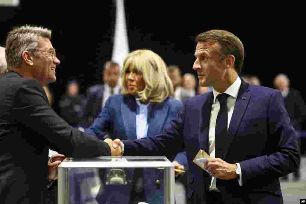 French President Emmanuel Macron, right, shakes hands with a polling station official during the European election, June 9, 2024 in Le Touquet-Paris-Plage, northern France.