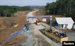 Sejumlah pekerja menaiki truk memasuki wilayah utama pemerintahan di Ibu Kota Nusantara, di Sepaku, Kalimantan Timur, 8 Maret 2023. (Foto: Willy Kurniawan/Reuters)