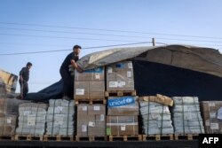 Seorang pria menurunkan bantuan kemanusiaan saat konvoi truk memasuki Jalur Gaza dari Mesir melalui perbatasan Rafah, 21 Oktober 2023. (Foto: AFP)