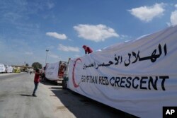 Pengemudi Mesir menutupi truk bantuan kemanusiaan mereka saat menunggu untuk menyeberangi perbatasan Rafah antara Mesir dan Jalur Gaza, 23 Maret 2024. (Foto: AP)