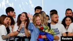 Italy's Prime Minister Giorgia Meloni gestures, as she holds a bouquet of flowers, during a "Brothers of Italy" (Fratelli d'Italia) right-wing party conference in Pescara, April 28, 2024. 