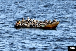 FILE - Migrants of African origin are crammed on board a small boat as Tunisian coast guards prepare to transfer them onto their vessel, at sea between Tunisia and Italy, Aug. 10, 2023.