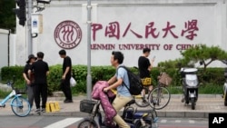 北京街頭人們經過中國人民大學校園外牆的標識。（2024年7月22日）