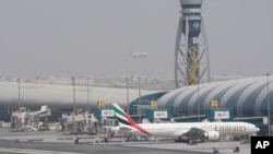 FILE - An Emirates jet waits at the gate as another prepares to land in Dubai, United Arab Emirates, on Aug. 17, 2022, shortly before the airline suspended flights to Nigeria. Nigerian authorities on Sept. 12, 2023, announced that the UAE would lift a year-old visa ban.