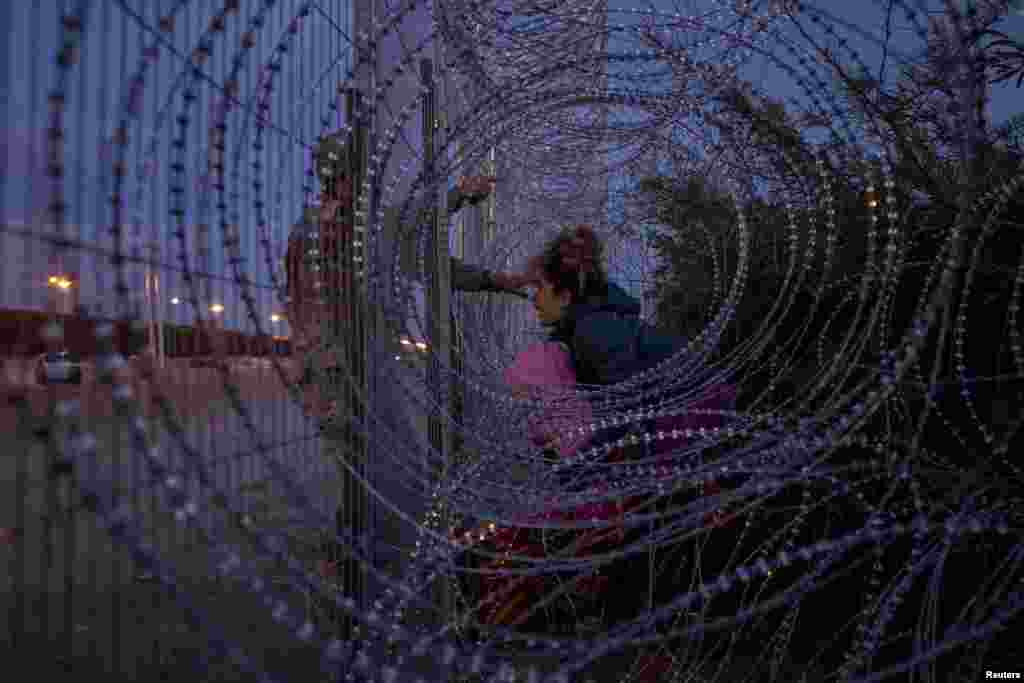 Eliana, 22, a migrant from Venezuela, holds her three-year-old daughter Chrismarlees as she shouts towards an Army National Guard soldier in El Paso, Texas, March 26, 2024.
