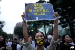 Seorang anggota kelompok pecinta lingkungan membentangkan poster dalam aksi protes menentang keputusan Jepang untuk membuang air limbah PLTN Fukushima ke laut, dalam aksi di Seoul, Korea Selatan, pada 22 Agustus 2023. (Foto: AP/Lee Jin-man)