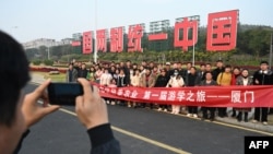 中国福建厦门竖立起一个台湾金门岛可以看到的“一国两制统一中国”的大型标语牌，旅游者在前拍照。（2024年1月12日）