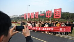 中國福建廈門豎立起一個台灣金門島可以看到的「一國兩制統一中國」的大型標語牌，旅遊者在前拍照。 （2024年1月12日）