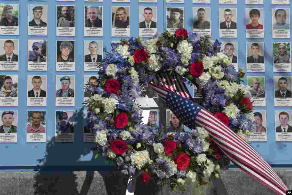 Flowers placed by the President Joe Biden at the Memorial Wall of Fallen Defenders of Ukraine in Russian-Ukrainian War with photos of killed soldiers in Kyiv, Feb. 20, 2023. 