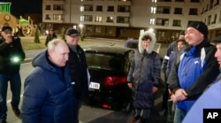 Presiden Rusia Vladimir Putin berbicara dengan penduduk setempat selama kunjungannya ke Mariupol di wilayah Donetsk yang dikuasai Rusia, Ukraina. (Foto: via AP)