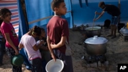 FILE — Palestinian children wait for food in a displaced tent camp in Khan Younis, southern Gaza Strip, Oct. 25, 2023. Even before the Israel-Hamas war broke out, Palestinians struggled to fulfill their basic needs, according to a Gallup poll. 