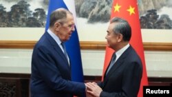Menteri Luar Negeri Rusia Sergei Lavrov berjabat tangan dengan Menteri Luar Negeri China Wang Yi dalam pertemuan di Beijing, China, 16 Oktober 2023. (Kementerian Luar Negeri Rusia/Handout via REUTERS)
