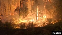 FILE - A fire burns close to the highway near Sorrento, British Columbia, Canada, on Aug. 18, 2023, in this screen grab obtained from social media video.
