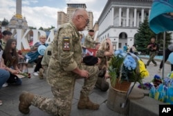 Orang-orang meletakkan bunga untuk mengenang tentara yang tewas dalam perang dengan Rusia di Lapangan Kemerdekaan di Kyiv, Ukraina, 23 Mei 2024. (AP Photo/Efrem Lukatsky)