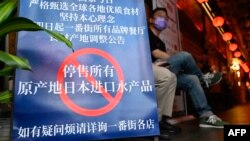 FILE - People are seen at an area of Japanese restaurants where there is a sign reading 'Suspend the sale of all fish products imported from Japan', in Beijing on Aug. 27, 2023.