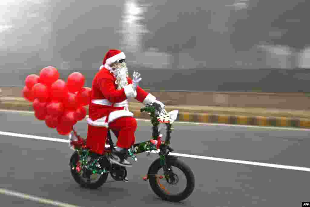 Sinterklas mengendarai sepeda di sepanjang jalan yang diselimuti kabut saat Natal di New Delhi, India.