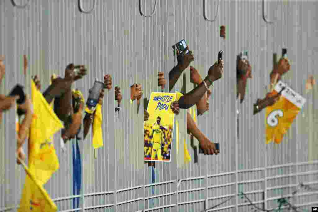 Para fans membawa poster MS Dhoni dari Chennai Super Kings dan memotret melalui pagar sambil menunggu dimulainya pertandingan kriket Liga Utama India antara Chennai Super Kings dan Punjab Kings di Chennai, 1 Mei 2024. (AP/R.Parthibhan)