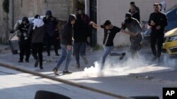 Seorang demonstran Palestina menendang tabung gas air mata saat bentrok dengan pasukan Israel saat penggerebekan di Kota Nablus, Tepi Barat, Senin, 3 April 2023. (Foto: AP)