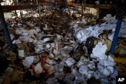Buku-buku yang terbakar terlihat di bengkel yang rusak di percetakan terbesar Ukraina yang hancur akibat serangan rudal mematikan Rusia yang menewaskan tujuh warga sipil di Kharkiv, Ukraina, 24 Mei 2024. (Foto: via AP)