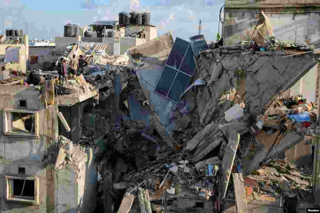 Warga Palestina memeriksa lokasi serangan Israel di sebuah rumah di Rafah, di Jalur Gaza selatan, di tengah konflik yang sedang berlangsung antara Israel dan kelompok Islam Palestina Hamas.