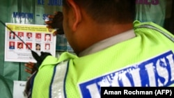 ILUSTRASI - Seorang polisi menempelkan pengumuman terkait Daftar Pencarian orang (DPO) Tindak Pidana Teroris di sebuah jendela di Malang, Jawa Timur, 30 September 2011, sebagai bagian dari upaya negara untuk memerangi aksi terorisme. (AMAN ROCHMAN/AFP)