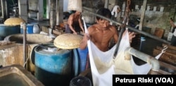 Pekerja menyaring tahu saat proses memasak kedelai menjadi tahu (foto Petrus Riski-VOA)