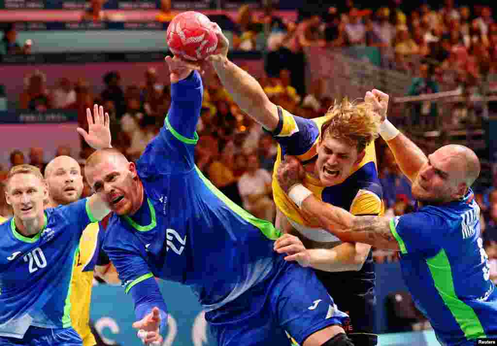 Matej Gaber of Slovenia, Karl Wallinius of Sweden and Borut Mackovsek of Slovenia attempt to score a goal during the men's handball preliminary round group A match at the South Paris Arena 6 in Paris, France, at the Paris Olympics. 