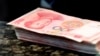 FILE - Chinese 100 yuan banknotes are seen on a counter of a branch of a commercial bank in Beijing, March 30, 2016. 