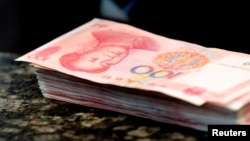 FILE - Chinese 100 yuan banknotes are seen on a counter of a branch of a commercial bank in Beijing, March 30, 2016. 