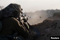 Seorang tentara Israel menembakkan senjatanya selama operasi darat tentara Israel melawan Hamas, di Jalur Gaza, 13 November 2023. (Foto: via Reuters)