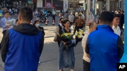 在中國前總理李克強的安徽合肥故居前，身穿藍色馬甲的保全人員注視著排隊為李克強鮮花的民眾隊伍。 （2023年11月2日）