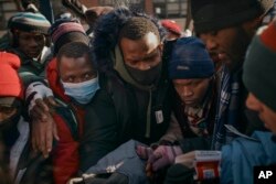 Migrants pick up clothes as mutual aid groups distribute food and clothes under cold weather near the Migrant Assistance Center at St. Brigid Elementary School, Jan. 20, 2024, in New York.