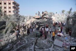 Warga Palestina mencari korban selamat pasca penyerangan Israel di Jalur Gaza di Deir Al-Balah, Minggu, 22 Oktober 2023. (Foto: AP)