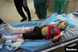 A Palestinian girl, wounded in Israeli strikes, lies on a bed at a hospital in Khan Younis in the southern Gaza strip, October 16, 2023.