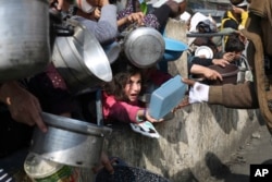 Warga Palestina, termasuk anak-anak, antre untuk mendapatkan makanan gratis selama serangan udara dan darat Israel yang sedang berlangsung di Jalur Gaza di kota Rafah.