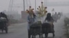 Corn sellers push their hand-carts in Lahore, Pakistan, Nov. 8, 2023, as smog hangs over city.