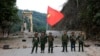 FILE - Anggota Tentara Aliansi Demokratik Nasional Myanmar berpose dengan bendera kelompok tersebut di depan jembatan Kunlong di negara bagian Shan, Myanmar, 12 November 2023. 