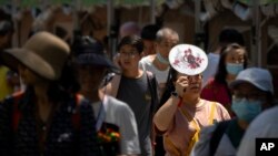 2023年6月22日,在中國正值人們慶祝端午節賽龍舟之時,然而氣溫卻熱得讓人不可思議。一位來公園觀看龍舟賽的婦女用扇子舉在頭上遮擋陽光。