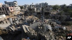 Warga Palestina melihat bangunan-bangunan yang hancur akibat serangan Israel di Jalur Gaza di Rafah, Senin, 4 Desember 2023. (AP Photo/Hatem Ali)