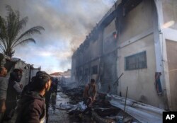 Palestinians try to extinguish a fire at a building of an UNRWA vocational training center which displaced people use as a shelter, after being targeted by Israeli tank shill in Khan Younis, southern Gaza Strip, Jan. 24, 2024.
