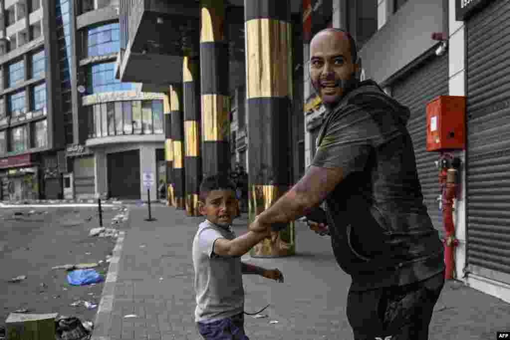 A man and young child react during clashes between Israeli soldiers and Palestinian gunmen in the center of Jenin in the occupied West Bank. In Jenin, the streets were largely deserted and most shops were closed after loud explosions and clashes were heard during the night while Israeli bulldozers caused damage to roads and infrastructure including water systems, according to Palestinian officials in the northern West Bank. 