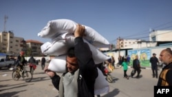 Seorang pria di Rafah, selatan Gaza, tampak membawa sejumlah karung berisi kebutuhan sehari-hari yang merupakan bagian dari bantuan kemanusiaan untuk Gaza, pada 26 November 2023. (Foto: AFP/Mohammed Abed)