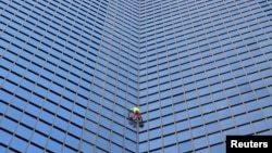 "Spiderman" Prancis Alain Robert memanjat gedung pencakar langit "Tour TotalEnergies Coupole" untuk menyerukan "Perdamaian di Timur Tengah" di Puteaux di distrik keuangan La Defense di Puteaux, dekat Paris, Prancis hari Senin (6/11). (Reuters) 